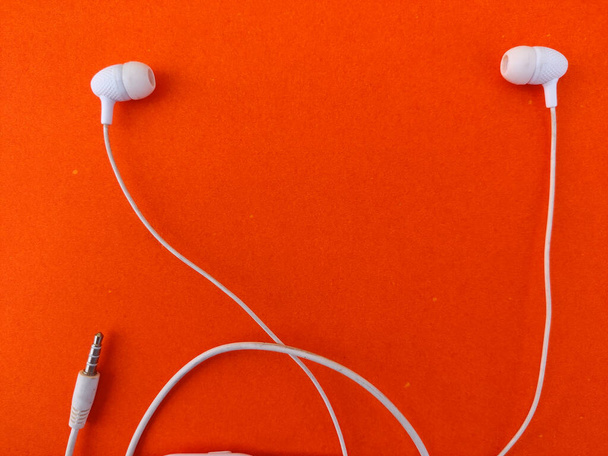 Copie el espacio entre dos audífonos blancos aislados sobre fondo naranja - Foto, Imagen