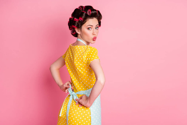Back rear spine view photo of housewife with hair curlers wear apron send air kiss isolated pastel color background - Foto, Imagen