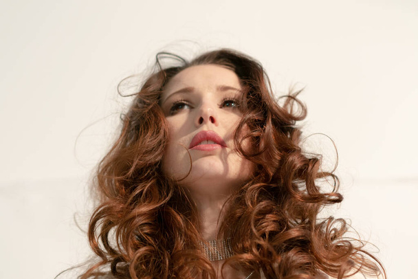 スタジオでふわふわの髪をした若い可愛い女性の肖像画 - 写真・画像