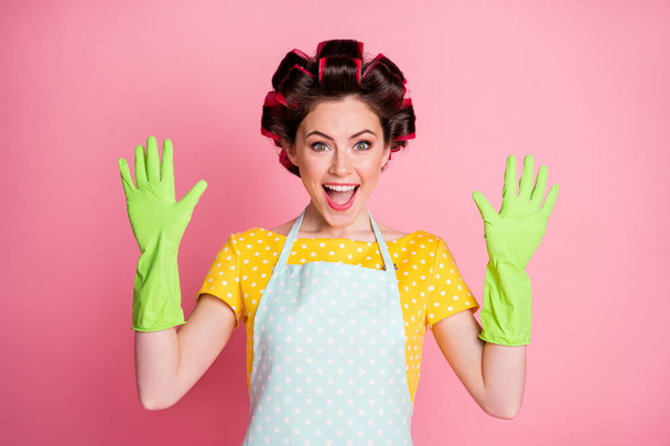 Portrait of astonished positive girl hold hands wear rubber gloves hair curlers isolated pastel color background - Foto, Imagem
