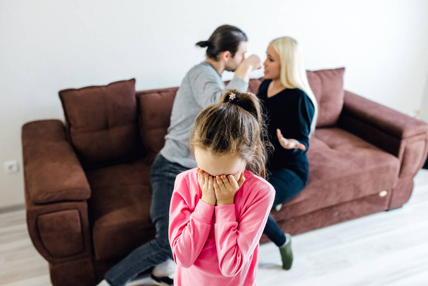 Unhappy little kid girl covering face, suffering from noisy parents argument, angry mother and father shouting and quarreling on background, family conflict, children and divorce - Fotoğraf, Görsel