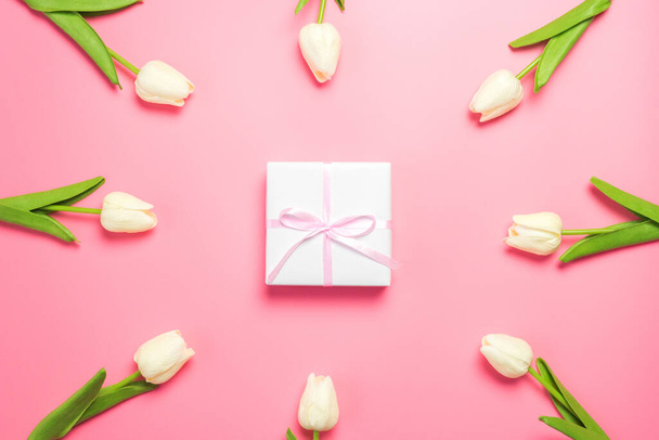 Άνοιξη λουλούδια λευκά τουλίπες σε ροζ φόντο με κουτί δώρου. Ημέρα της μητέρας ή σύνθεση της ημέρας της γυναίκας. - Φωτογραφία, εικόνα