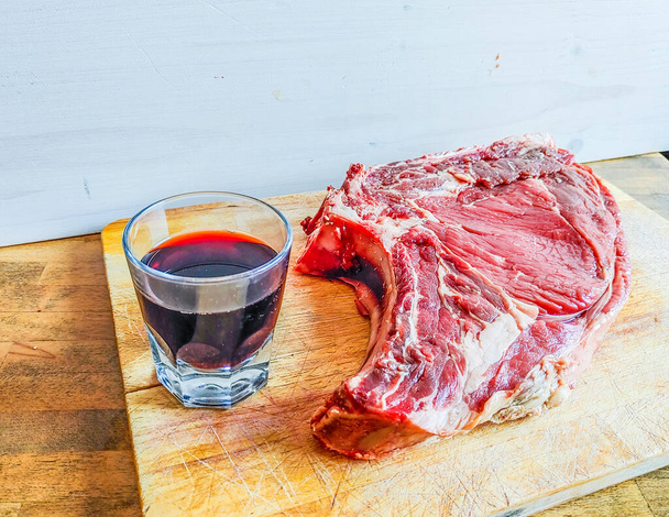 steak de boeuf sur l'os, bien mûri, prêt pour votre barbecue et votre déjeuner, steak florentin, avec un verre de bon vin rouge authentique - Photo, image