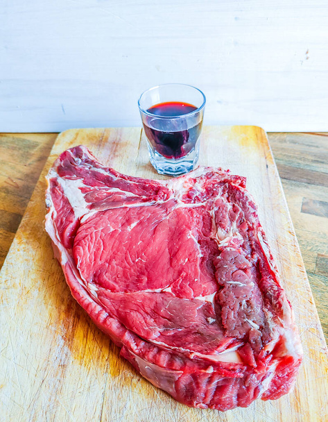stek wołowy na kości, dobrze dojrzały, gotowy na grilla i obiad, florencki stek, ze szklanką dobrego prawdziwego czerwonego wina - Zdjęcie, obraz