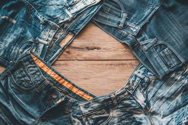 Several jeans are placed on the wooden floor. - Photo, image