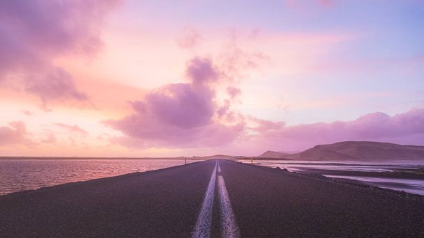 Пустая дорога прямо перед Дирхолай в Южной Исландии с красочным закатом.  - Фото, изображение