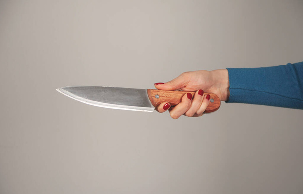 woman hand holding knife in back on gray background - Fotoğraf, Görsel