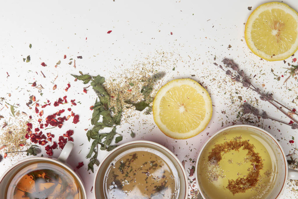 Herbal tea, top view. Dry herbs, lemon slices and tea cups on white. Herbs in bulk, zero waste and eco-friendly lifestyle, herbal medicine concept. - Fotoğraf, Görsel