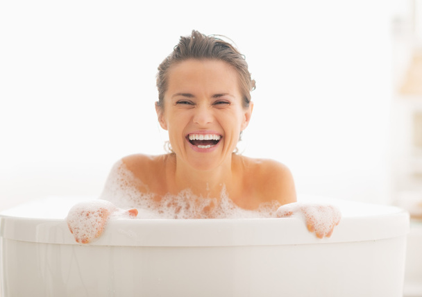 Smiling woman looking out from bathtub - Zdjęcie, obraz