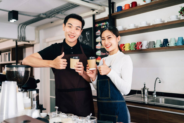 Kahve tezgahının içinde duran genç bir erkek ve bir bayan kafe sahibi. Girişimcilere küçük bir iş kurmaları için kahve yapma dersleri. Covid-19 salgını sırasında insanların yaşam tarzları. - Fotoğraf, Görsel