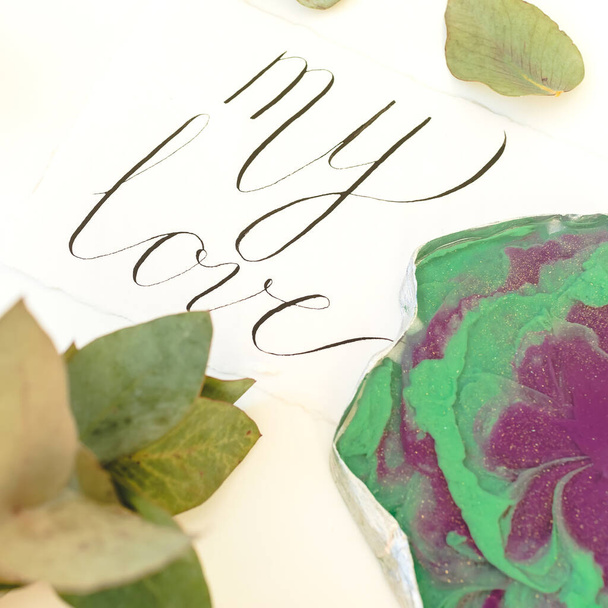 Resin art plate with "My love" in paper card and eucalyptus on white background. Top view - Photo, Image