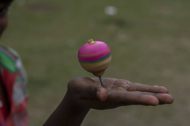 A spinning top or Lattu in Hindi spinning on a hand with selective focus. - Photo, Image