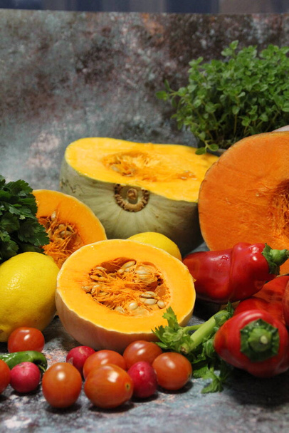 kleurrijke groenten, tomaten, paprika 's en grote oranje pompoenen doormidden gesneden, selderij en verse oregano en peterselie op de achtergrond, gezond voedsel - Foto, afbeelding