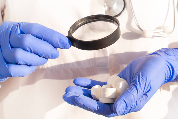 Apotheker of expert op het gebied van farmaceutische inspectie identificeert pillen. Onderzoek, controle en vaststelling van namaak of namaak van geneesmiddelen - Foto, afbeelding