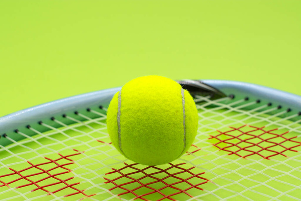 теннисный мяч с ракеткой на зеленом фоне. Концепция спорта. - Фото, изображение
