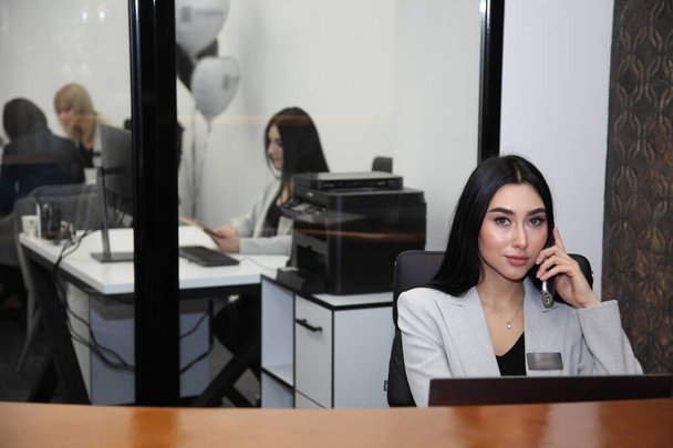 VINNYTSIA, UKRAINE - 1. FEBRUAR 2021: Schöne Frau arbeitet mit einem Kunden im Büro - Foto, Bild
