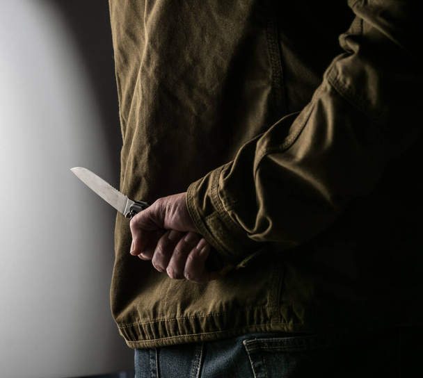 Man hiding a knife behind his back - Foto, Imagen