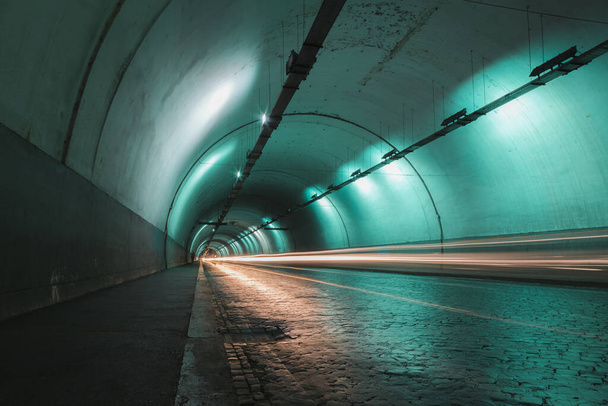 Sentieri di luce lasciati indietro mentre il traffico si muove attraverso un tunnel cittadino a Roma. - Foto, immagini
