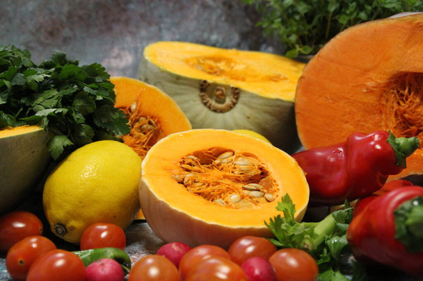 värikkäitä vihanneksia, tomaatteja, paprikoita ja suuria oransseja kurpitsoja leikattu kahtia, selleriä tuoretta oreganoa ja persiljaa taustalla, terveellistä ruokaa, selleriä - Valokuva, kuva