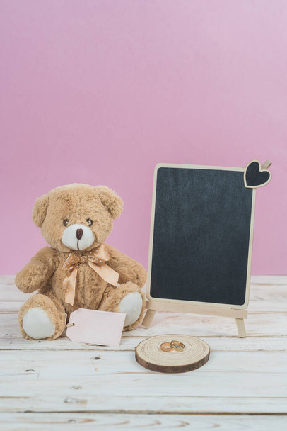 Valentines day teddy bear on white table and blackboard and pink background - Photo, image