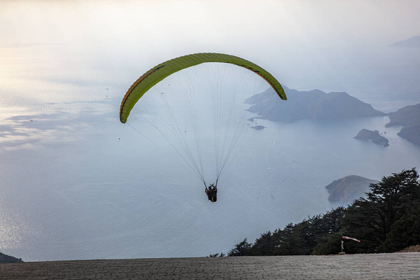 Parapente en el cielo. Parapente tándem volando sobre el mar con montañas al atardecer. Vista aérea del parapente y Laguna Azul en Oludeniz, Babadag, Mugla, Turquía. - Foto, imagen