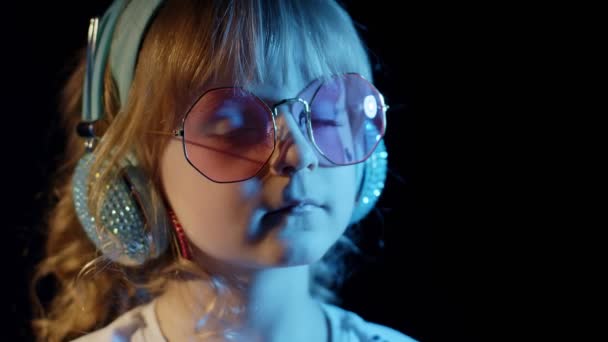 Stylowe, modne dziecko w okularach przeciwsłonecznych na imprezie disco cyberpunk club patrzące w kamerę i uśmiechnięte - Materiał filmowy, wideo