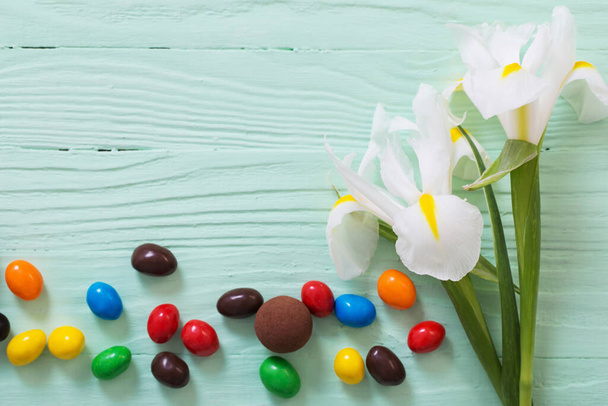 Easter chocolate eggs and flowers on green wooden background - Photo, Image