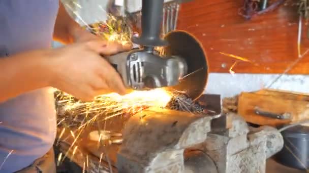 Close up view on metal processing with circular saw. Hands of professional mechanic holding instrument and grinding metal. Skillful repairer cutting iron detail in garage or workshop. Slow motion - Footage, Video