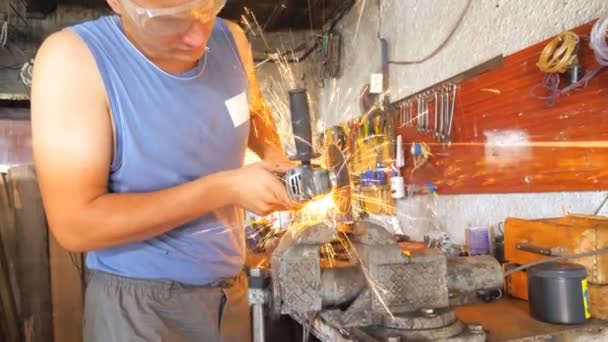 Professional mechanic processing metal detail with circular saw at workshop. Skillful repairer cutting metal using electric grinding wheel in garage. Bright hot sparks flying around. Slow motion - Footage, Video