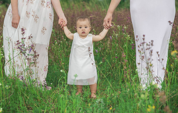 schattig baby in avond jurk houdt handen van mam en ouder zus - Foto, afbeelding