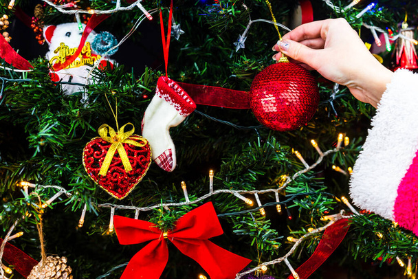 Decoreren kerstboom, hand zetten kerstversiering op sparren takken. Kerst opknoping decoraties. - Foto, afbeelding