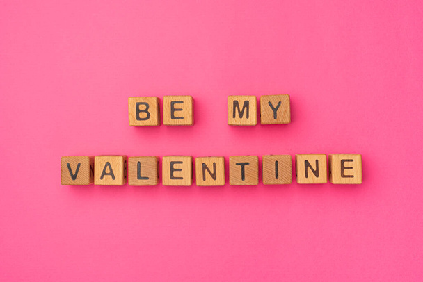 Cubi di legno con la frase Be My Valentine su uno sfondo rosa colorato vuoto. Le parole d'amore sono fatte di lettere da legno durante Giorno di San Valentino e per la Sua ragazza, fidanzato, moglie, marito - Foto, immagini