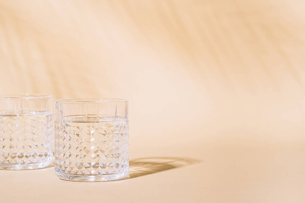 Glass of water on pastel background with hard shadow - Foto, imagen