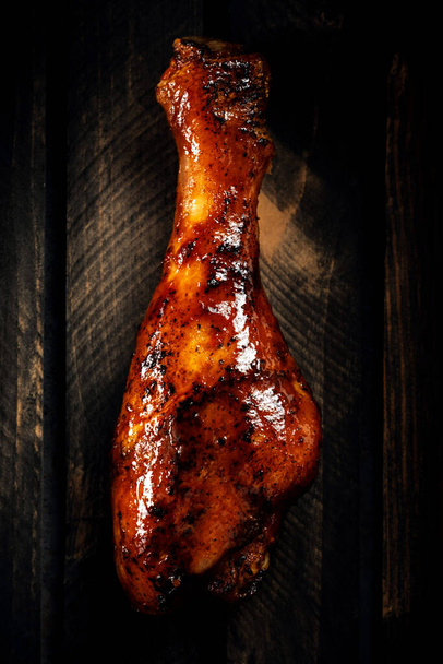 pierna de pollo a la parrilla en salsa barbacoa sobre un fondo de madera oscura - Foto, Imagen