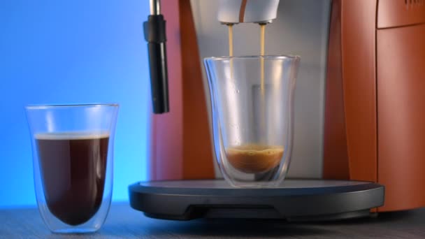 Kávovar plní u kávy skleněný šálek s dvojitými stěnami. Nedaleko je další skleněný šálek kávy. - Záběry, video