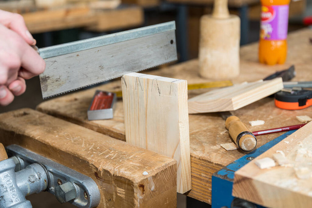 Carpintero con una sierra de mano durante la carpintería en el taller - sierra de madera de primer plano - Foto, imagen