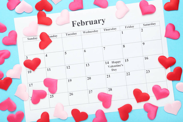 February calendar with colorful fabric hearts on blue background - Fotó, kép