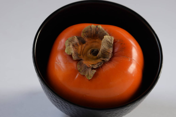 Closeup of fresh persimmon fruit which bright red orange in color. It is available in east Asian countries like Japan and imported to India - Photo, Image