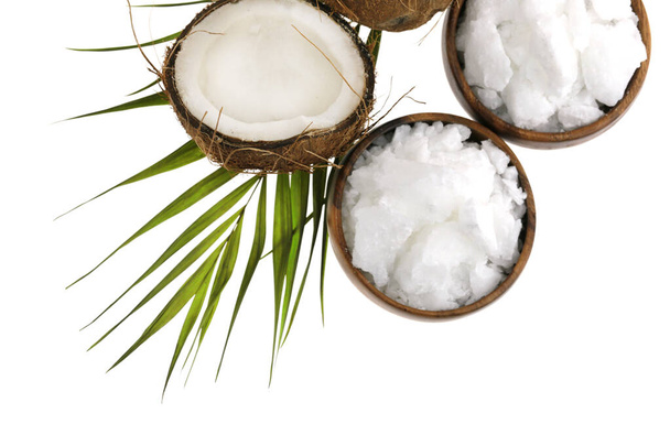 Kokosnussöl rein biologisch. Kokosöl in einer Tasse und Kokosfrüchte in Nahaufnahme mit grünem Palmblatt auf weißem Hintergrund - Foto, Bild