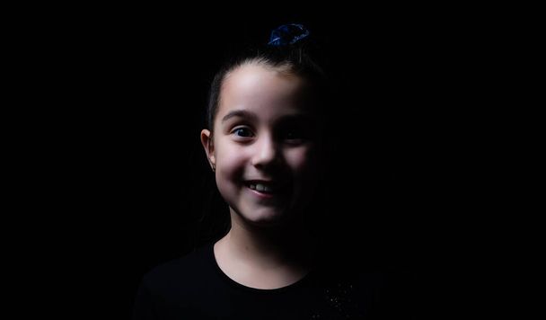 Closeup portrait of serious little girl isolated on black background - Фото, зображення