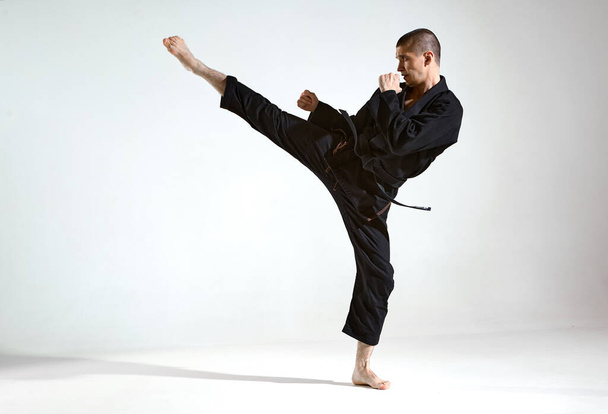 Siyah kimonolu dövüşçü stüdyo arka planında kudo tekniği gösteriyor. Fotokopi alanı, karışık dövüş konsepti. - Fotoğraf, Görsel