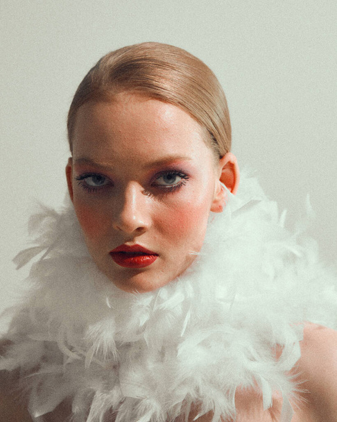 Romantic stylish young female model with white feathers collar, close up studio portrait of pretty girl - Foto, immagini