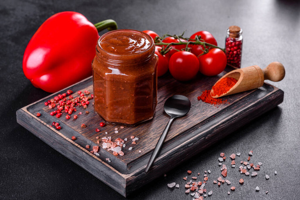 Pikantne przyprawy gruzińskiej kuchni adjika w misce z czerwonym pieprzem i czosnkiem na betonowym stole zbliżenie - Zdjęcie, obraz