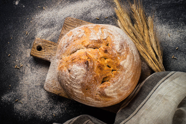 Fresh bread with whole grain flour at black table. - Фото, изображение