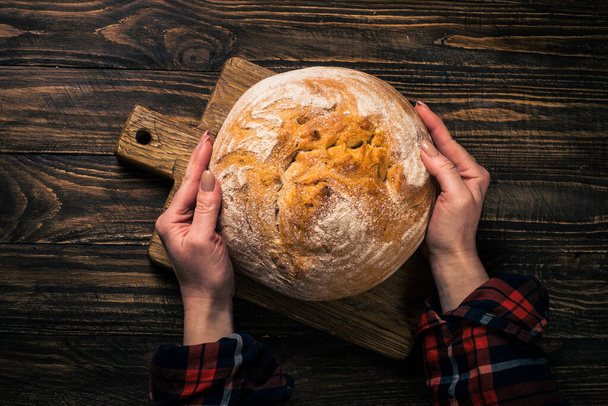 Vers zelfgemaakt brood aan rustieke houten tafel. - Foto, afbeelding