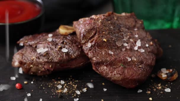sůl a koření padající na čerstvě grilované hovězí steak na černém kameni restaurace talíř - Záběry, video