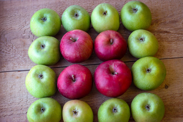 Grüne und rote Äpfel stehen auf einer Holzoberfläche - Foto, Bild