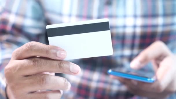 Mies käsi tilalla luottokortti ja käyttämällä älypuhelin ostoksia verkossa  - Materiaali, video