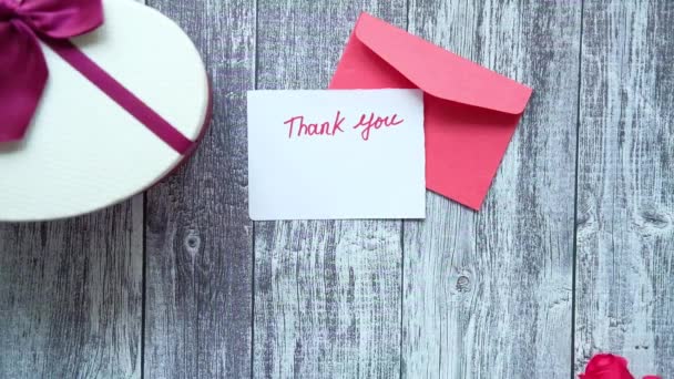 mensaje de agradecimiento, sobre y flor de rosa en la mesa de madera  - Metraje, vídeo