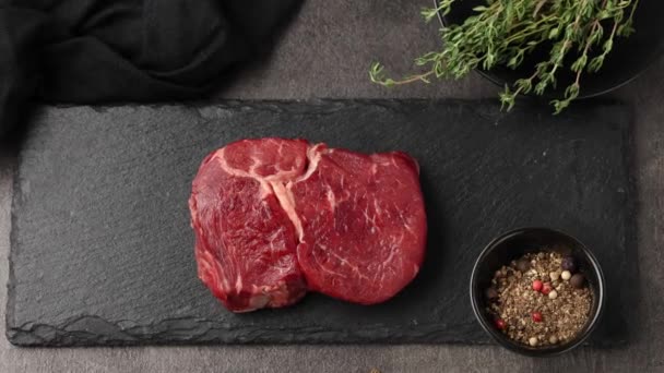 Frisches rohes Rindersteak in Scheiben geschnitten auf schwarzem Steinteller zoomen. Fleisch und Gewürze auf dem Küchentisch - Filmmaterial, Video